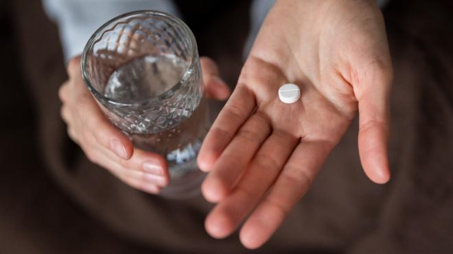 Persona con una pastilla en una mano y un vaso de agua en la otra (Foto: Freepik)