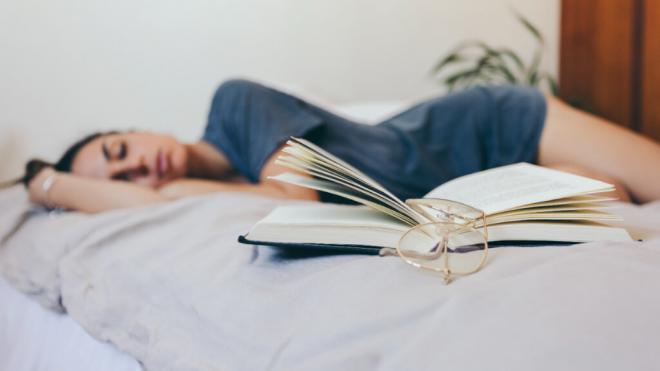 Mujer dormida junto a un libro y unas gafas (Foto: Freepik)