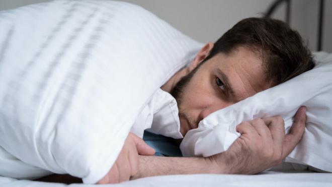 Hombre ansioso acostado en la cama (Foto: Freepik)