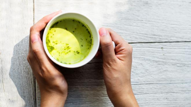 Persona sosteniendo con las dos manos una taza con té matcha (Foto:: Freepik)