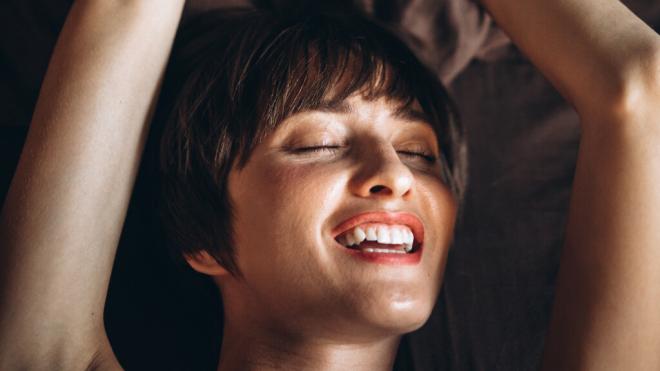 Mujer joven tumbada con cara de satisfacción (Foto: Freepk)