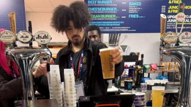 Un camarero con la camiseta del United en el Etihad (Redes sociales)