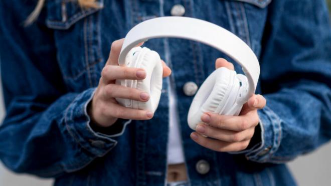 Joven sujetando auriculares (Foto: Freepik)