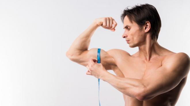 Hombre midiéndose con una cinta métrica el brazo (Foto: Freepik)
