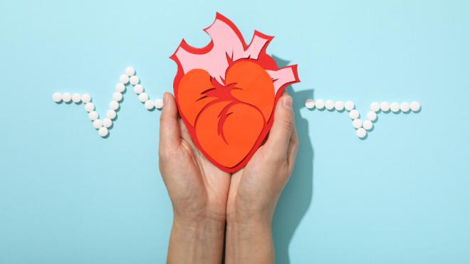 Persona sosteniendo una imagen de un corazón con un electrocardiograma simulado de fondo (Foto: Freepik)