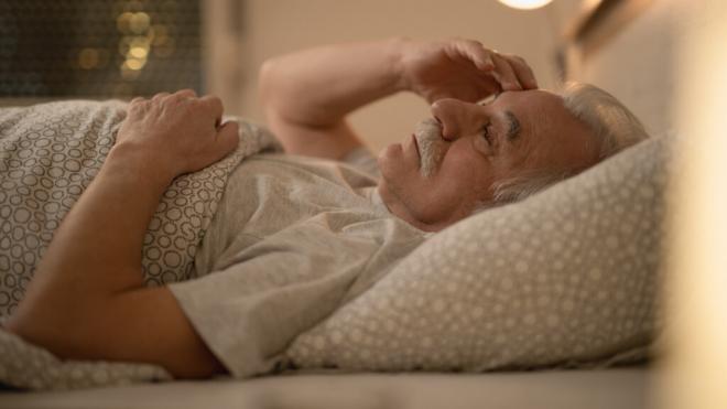 Hombre mayor intentando dormir en la cama (Foto: Freepik)