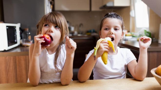 Dos niñas comiendo fruta (Foto: Freepik)