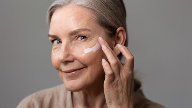 Mujer echándose crema antiarrugas en la cara (Foto: Freepik)