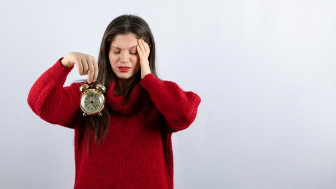 Mujer con síntomas de molestia sujetando un reloj (Foto: Freepik)