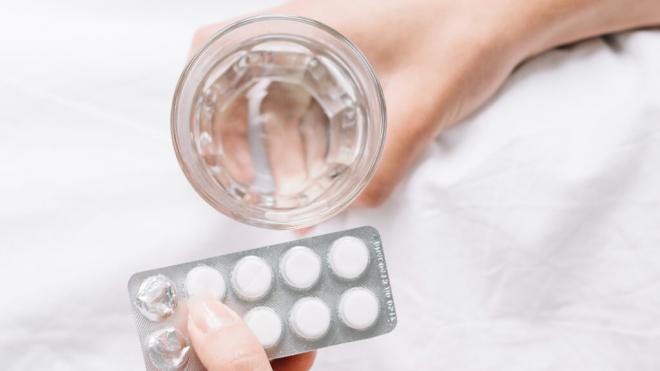 Persona sosteniendo unas pastillas y un vaso de agua (Foto: Freepik)