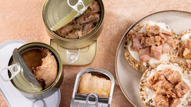 Diversas latas de atún junto a un plato de aperitivo (Freepik)