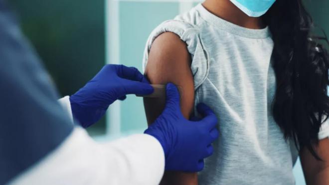 Sanitario poniendo una tirita a una niña tras inocularle una vacuna (Cochrane)