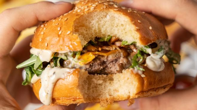 Persona comiéndose una hamburguesa de carne (Freepik)