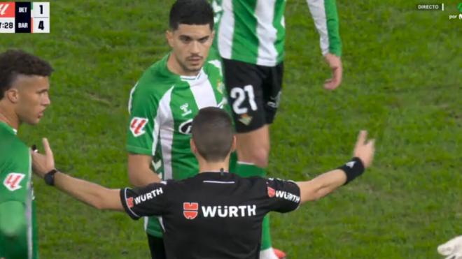 El árbitro, explicándole la acción a Marc Bartra.