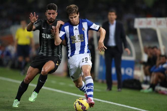 Los jugadores del Málaga y la Real luchan por el balón.