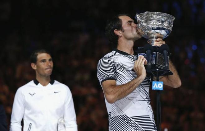 Federer levanta la Copa de campeón ante la mirada de Nadal.