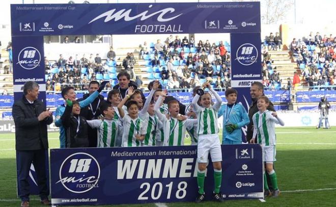 El Betis alevín levanta el trofeo de ganador.