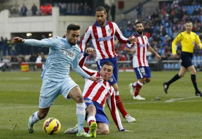 Rober Ibáñez intenta evitar una entrada de Giménez en el Atlético-Granada (Fotos: EFE)