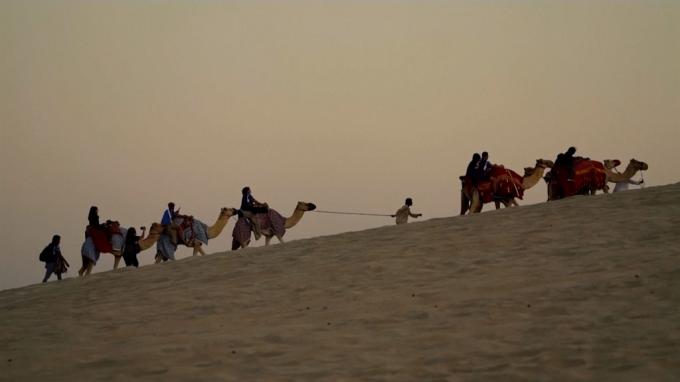 Turistas disfrutando del paseo en camello por el desierto de Qatar.