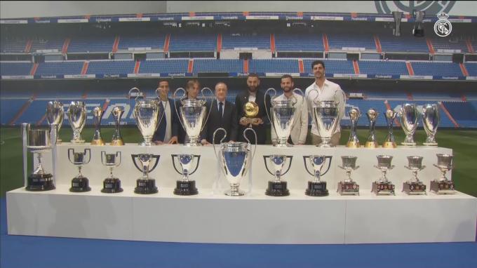 Karim Benzema posando con sus compañeros, el presidente y los trofeos que ha ganado